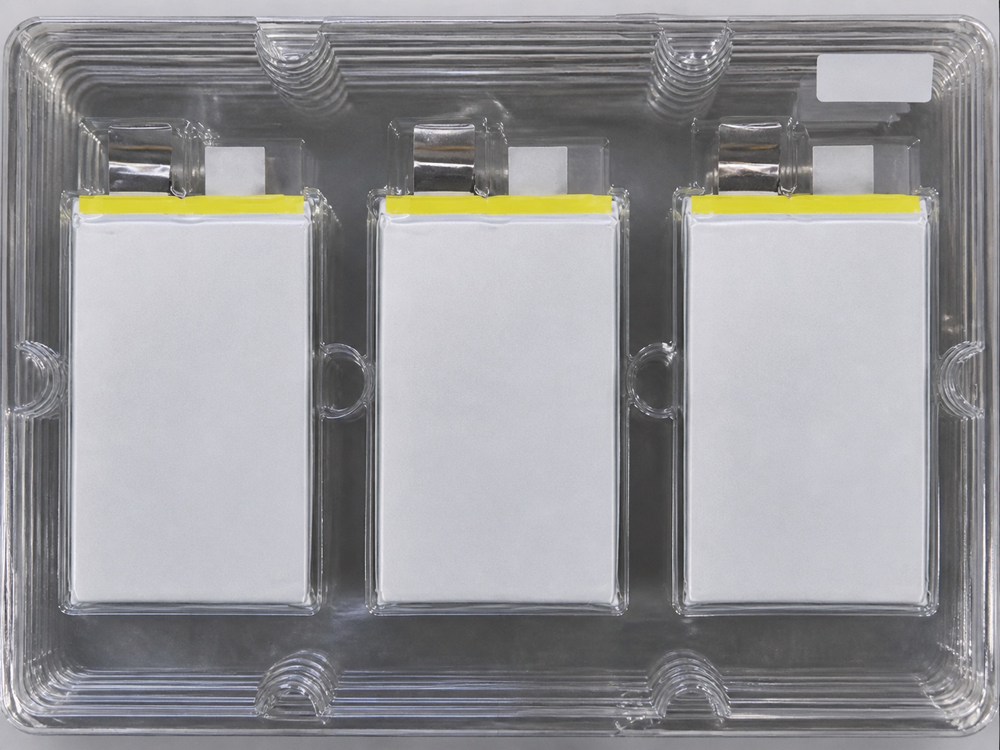Three real compact lithium pouch cells in a production tray